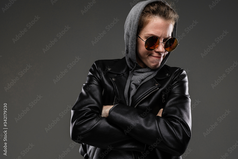 Brutal caucasian girl with rough facial features in a black jacket with a hood isolated on black background Brutal caucasian girl with rough facial features in a black jacket with a hood isolated on black background