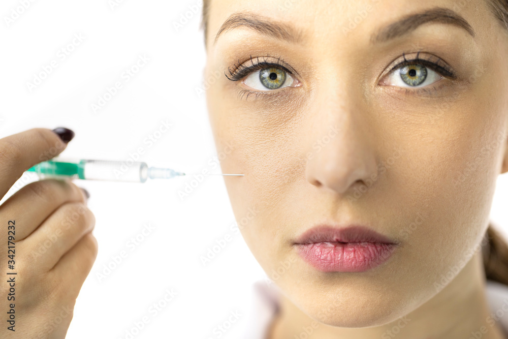 Young sexy woman with healthy skin filling female wrinkles on cheek with hyaluronic acid from syringe, white background. Cosmetology, facial botox injections, anti-aging treatment, face lift. Close up Young sexy woman with healthy skin filling female wrinkles on cheek with hyaluronic acid from syringe, white background. Cosmetology, facial botox injections, anti-aging treatment, face lift. Close up