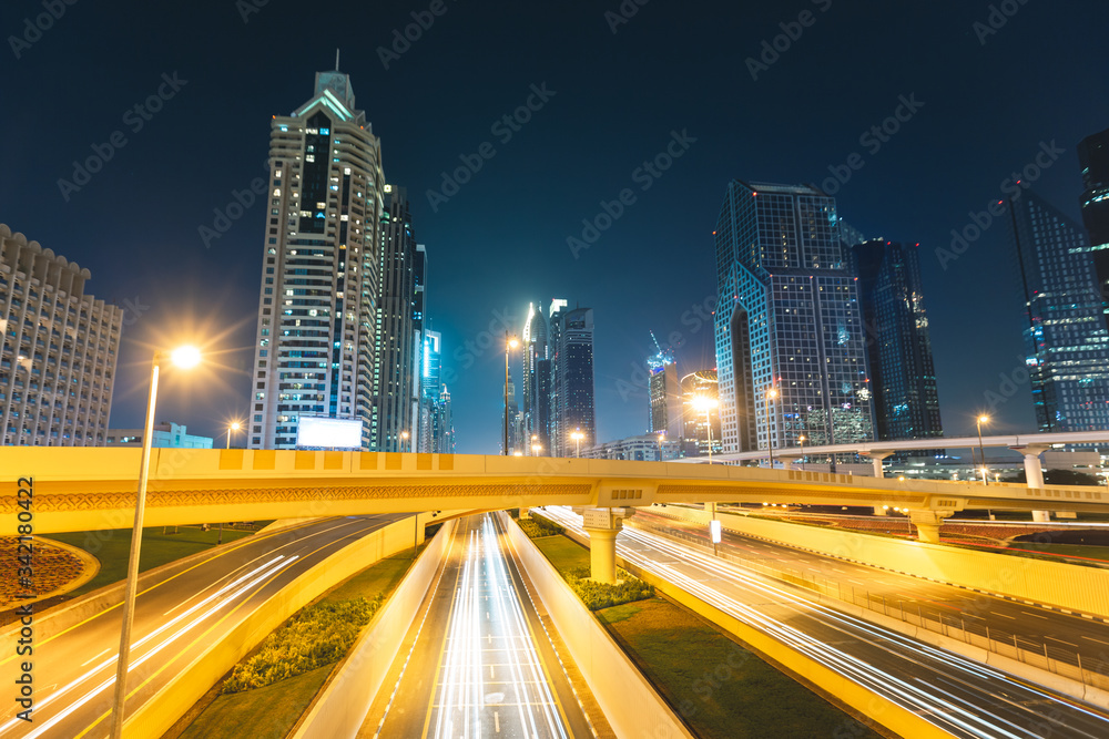Long exposure of cars passing on highway at night in front of skyscrapers Dubai - UAE