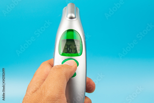 Man hand holding Temperature Measurement Device thermometer isolated on blue background