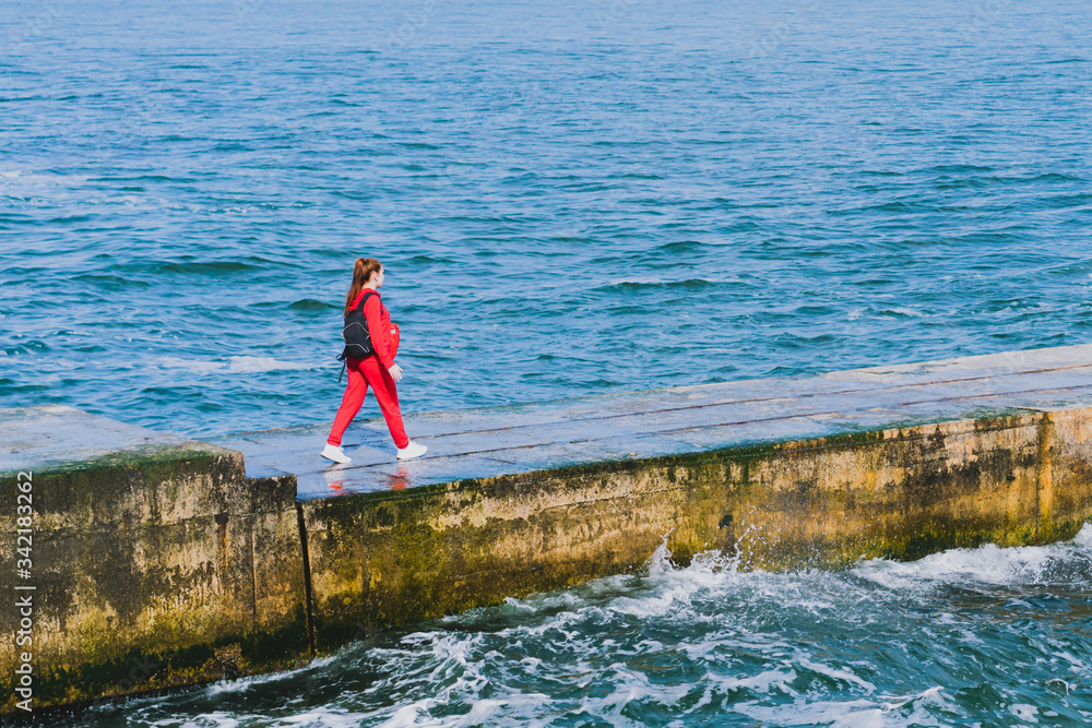 A girl in a red suit with small black backpack walking alone through ...