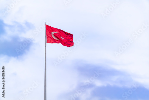 A huge Turkish flag waving in blue sky.