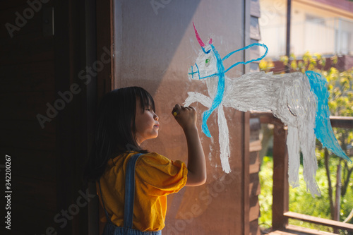 窓ガラスにユニコーンを描く女の子