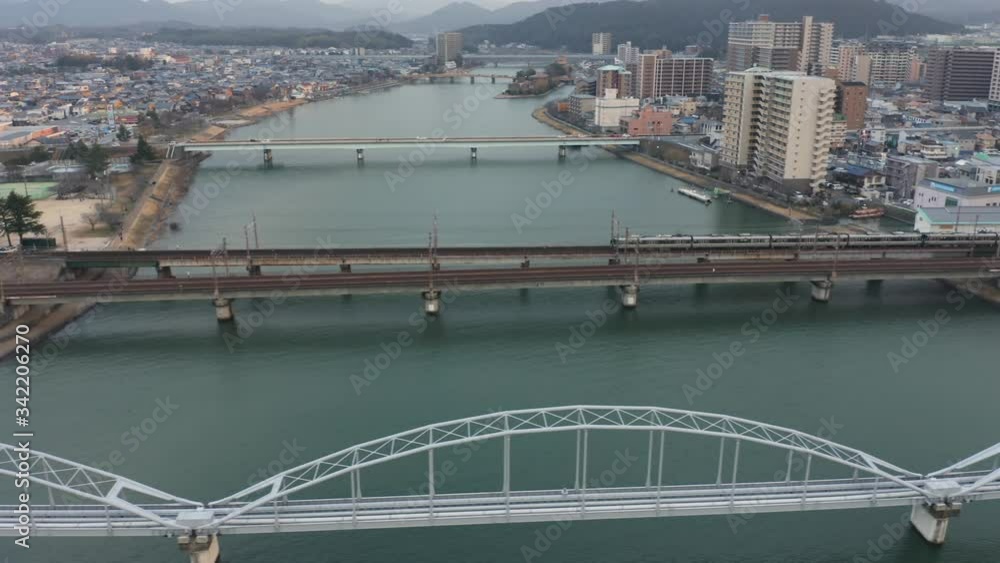 Train crossing bridge over Seta river, entering town of Ishiyama in Shiga, Japan