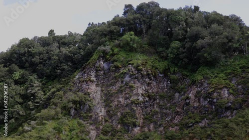 Wide shot of tall fumaroles emitting steam at Waimangu Volcanic Valley, Rotorua, New Zealand photo