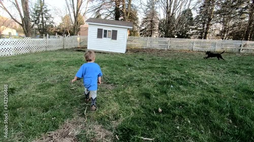 A Cute Little Boy Running Around The Farm Together With His Labrador Dog In The Park Of Crosswinds Marsh, Monroe County Michigan - Close Up Shot photo