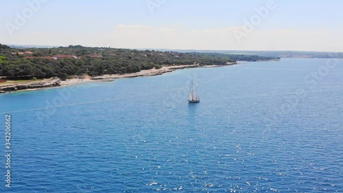 Aerial: high perspective of one sailing boat cruisng near the shore during the day. photo