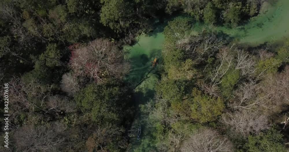 A high up drone shot of kayakers drifting down crystal clear river A high up drone shot of kayakers drifting down crystal clear river