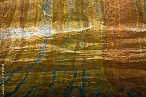 Isolated view of beautiful shades of gold and copper streaming down the face of a sandstone canyon wall.