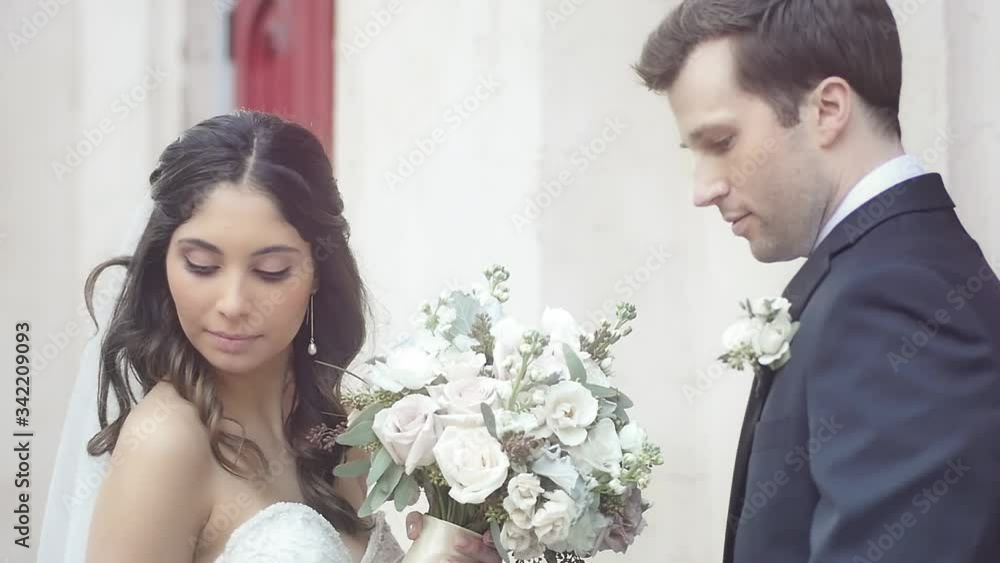 A bride and groom pose for serious wedding photos in front of a church A bride and groom pose for serious wedding photos in front of a church