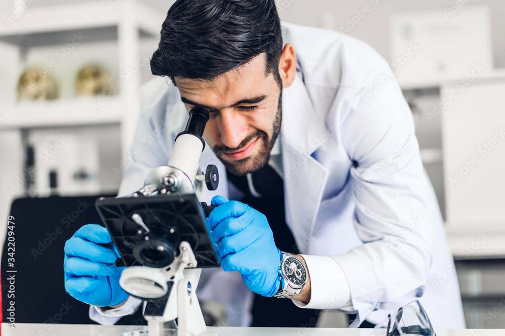 Professional scientist man doing a chemical experiment while making a research and using microscope with mixing chemicals in test tube at modern Laboratory Professional scientist man doing a chemical experiment while making a research and using microscope with mixing chemicals in test tube at modern Laboratory