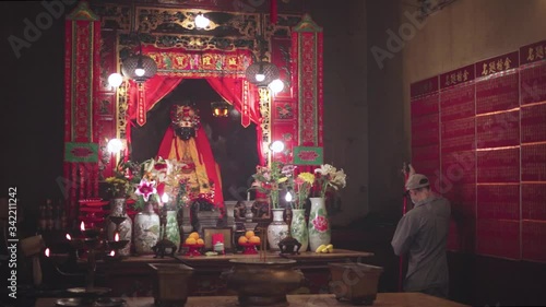 attendant sweeps near Chinese altar with god statue in Man Mo temple, Hong Kong