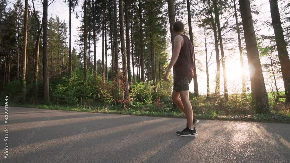 Male athlete taking a break in the forest and putting his hands in the hips Male athlete taking a break in the forest and putting his hands in the hips