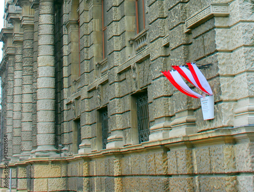 Part of an old stone high-rise building with hanging Austria flags on the corner. photo