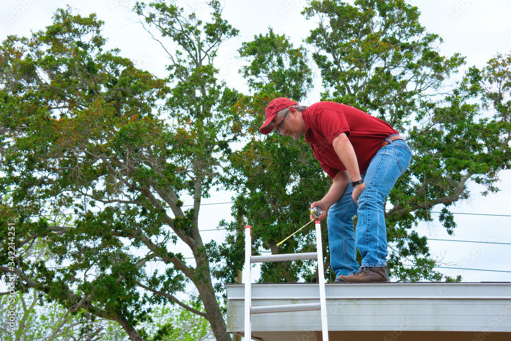 Φωτογραφία Wind mitigation inspector wearing safety goggles doing inspection on new roof to create a report and risk rating for homeowner to send to their insurance company to receive deductions in policy costs