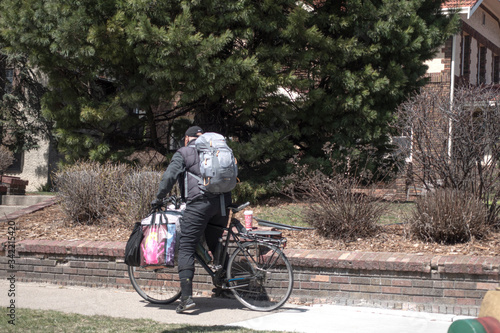Man on bicycle loaded with packages. Could be homeless or delivering food and supplies during the Covid-19 pandemic. St Paul Minnesota MN USA