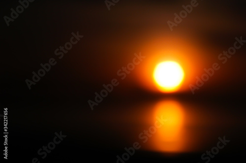 Abstract blur background of sunset The beach at sunset is blurry with bokeh light. Copy the area of ​​the outdoor summer. Orange and black filter style. Sunset background. © Charoenchai