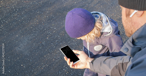 dad and preschool boy child at the street, looking at mobile device cellphone screen