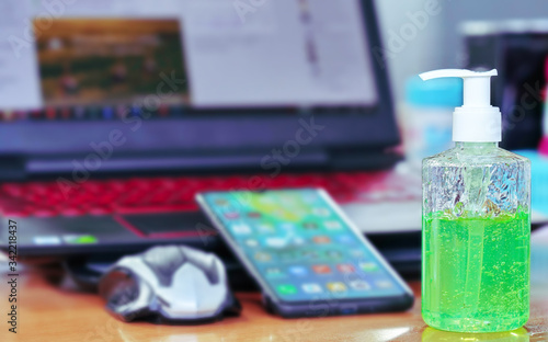 Green gel alcohol With a mixture of aloe vera in a pump-like bottle placed on the work desk  Together with the background of the smart phone and laptop.