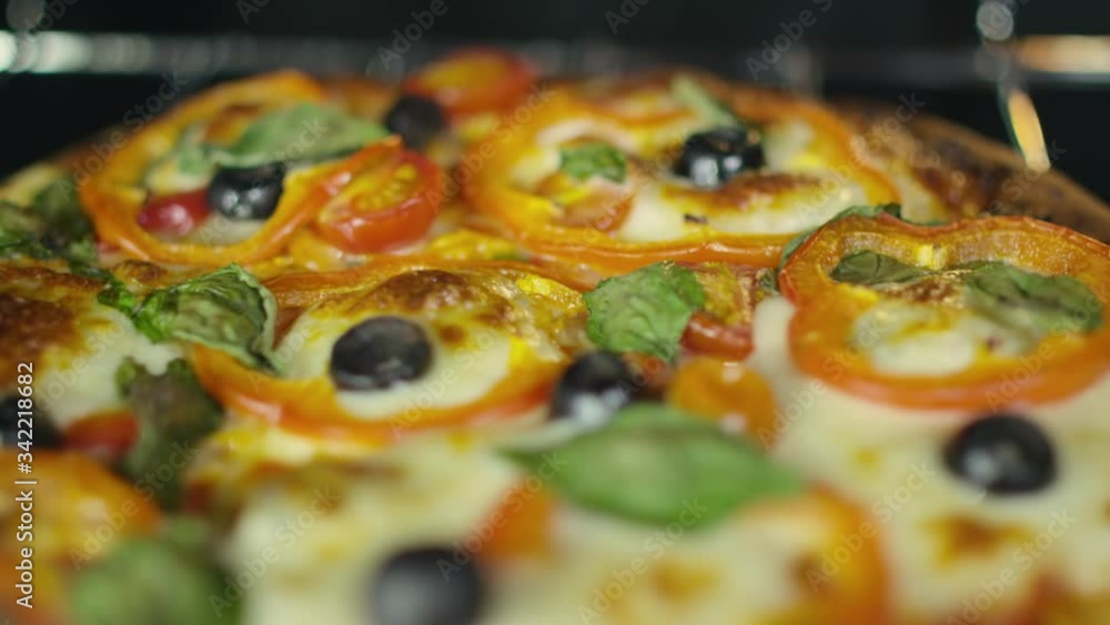 Extreme close-up over a gourmet pizza with tomato, olives and spinach toppings. Extreme close-up over a gourmet pizza with tomato, olives and spinach toppings.