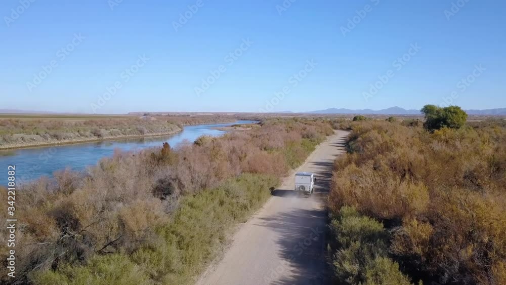 Aerial, drone shot following a camper van, driving on a dirt road, at the Colorado river, sunny day, in Arizona, USA Aerial, drone shot following a camper van, driving on a dirt road, at the Colorado river, sunny day, in Arizona, USA