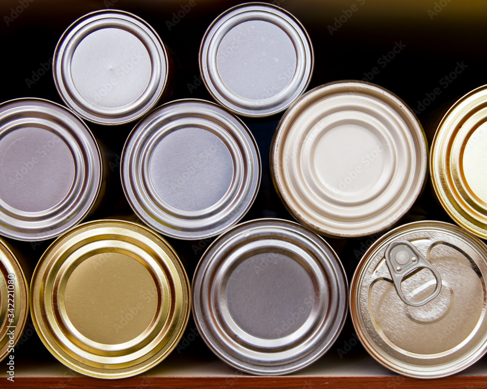 Many tin cans stacked on a pantry shelf in a row; hoarding or stocking up on canned goods in case of emergency Many tin cans stacked on a pantry shelf in a row; hoarding or stocking up on canned goods in case of emergency