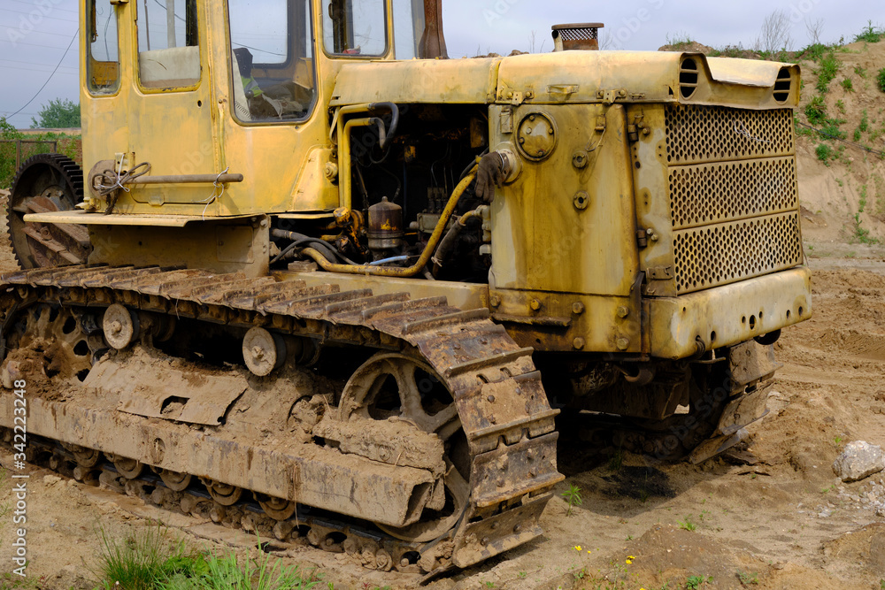 An old rusty, abandoned yellow bulldozer in a field.