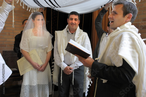 Fototapeta Rabbi blessing Jewish bride and a bridegroom in Jewish wedding ceremony
