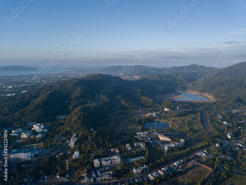 Beautiful lake located on a golf course surrounded by houses and mountains at dawn, photo from a drone. In the lake the reflection of the sky. Great background for travel and golf advertising.