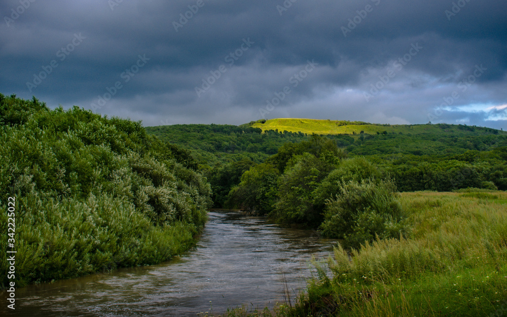 A crowded river with dense vegetation on the banks and hills in the background, backlit by the sun A crowded river with dense vegetation on the banks and hills in the background, backlit by the sun