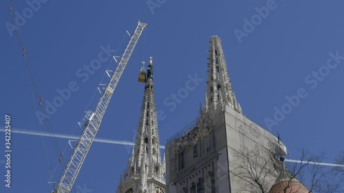Zagreb, Croatia - April 16, 2020: Timelapse of the dismantling of the earthquake damaged north tower of Zagreb Cathedral with a 500 ton crane and a plane flying in the background