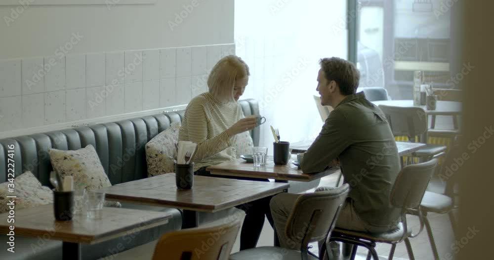 Young Adult couple having a good time together in cafe restaurant and drinking coffee at table Young Adult couple having a good time together in cafe restaurant and drinking coffee at table