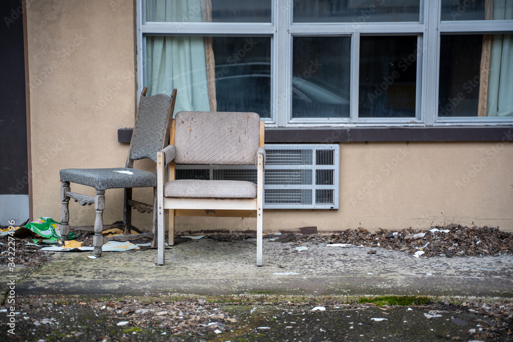 Old chairs in the front of an abandoned and vandalized motel