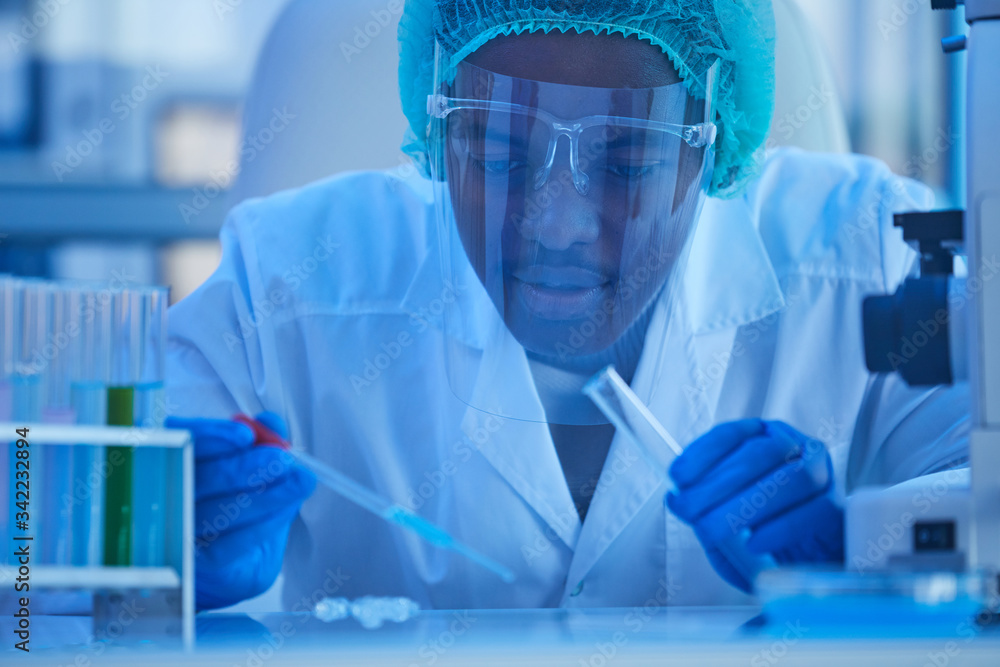 African doctor in protective mask working with samples from tube at medical laboratory African doctor in protective mask working with samples from tube at medical laboratory