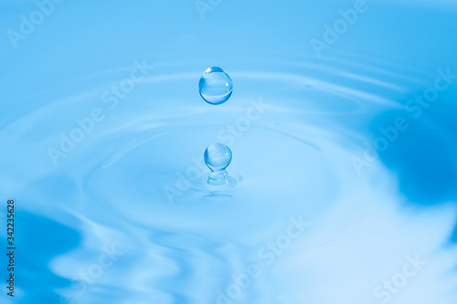 Two water drops splash and circle reflextion background.Close up fresh water drops falling into the water and ripples of light blue.