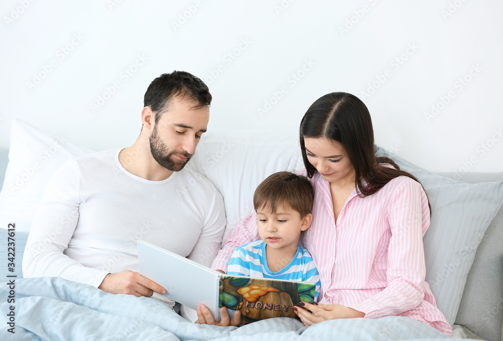 Happy family reading book in bedroom at home Happy family reading book in bedroom at home