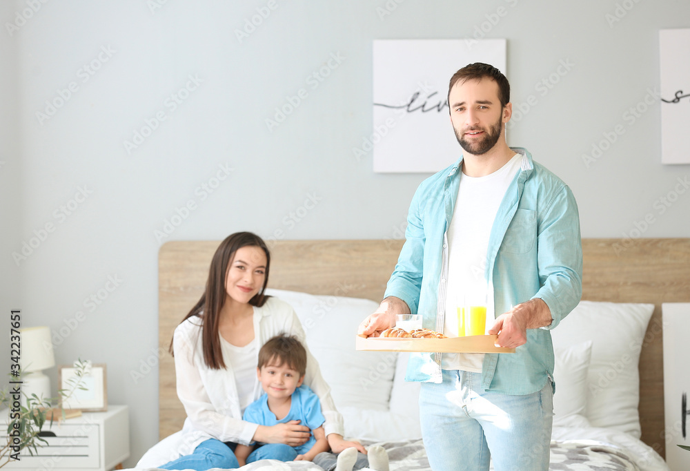 Obraz premium Happy man bringing his family breakfast in bed