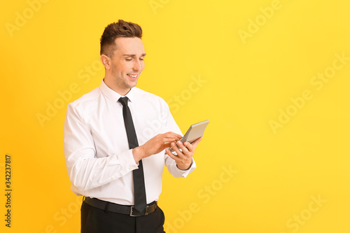 Young man with calculator on color background