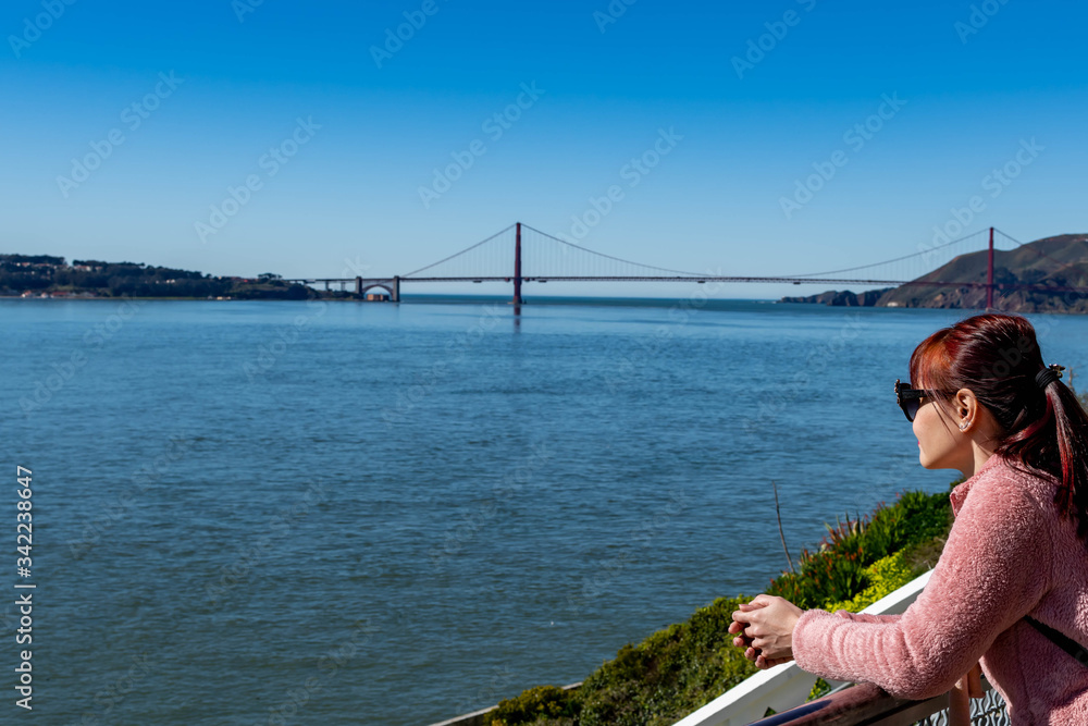Female adult while enjoying the skyline view of San Francisco USA and Golden Gate Bridge from Viewing Deck in Alcatraz Island Prison