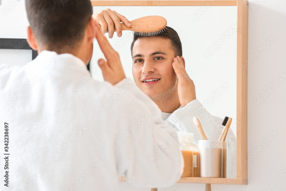 Obraz premium Handsome young man brushing hair at home