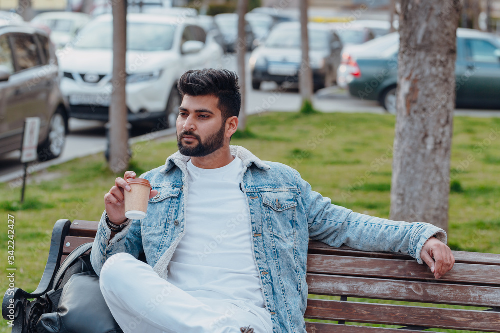 Bearded stylish indian man outdoors takes away coffee