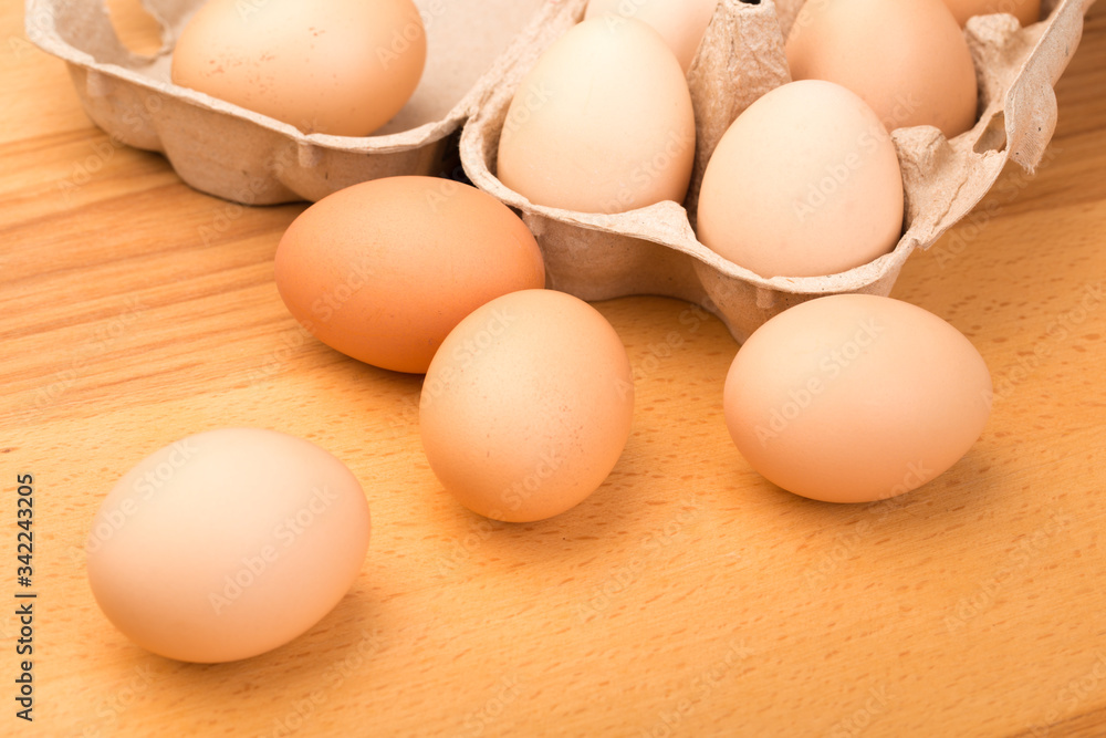 brown chicken eggs in an open cardboard box with eggs on a wooden table. Natural healthy food. brown chicken eggs in an open cardboard box with eggs on a wooden table. Natural healthy food.