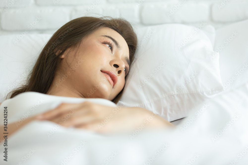 Asian woman cheerful and healthy and wearing white pajamas wake up on bed in bedroom in the morning.at home in holiday. Asian woman cheerful and healthy and wearing white pajamas wake up on bed in bedroom in the morning.at home in holiday.