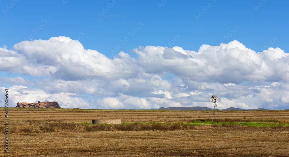 Landscape of a windmill and fields with white cloud and blue sky