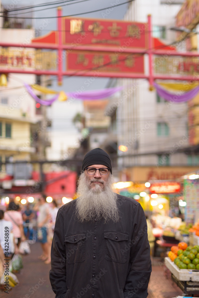 Mature bearded tourist man with eyeglasses in Chinatown