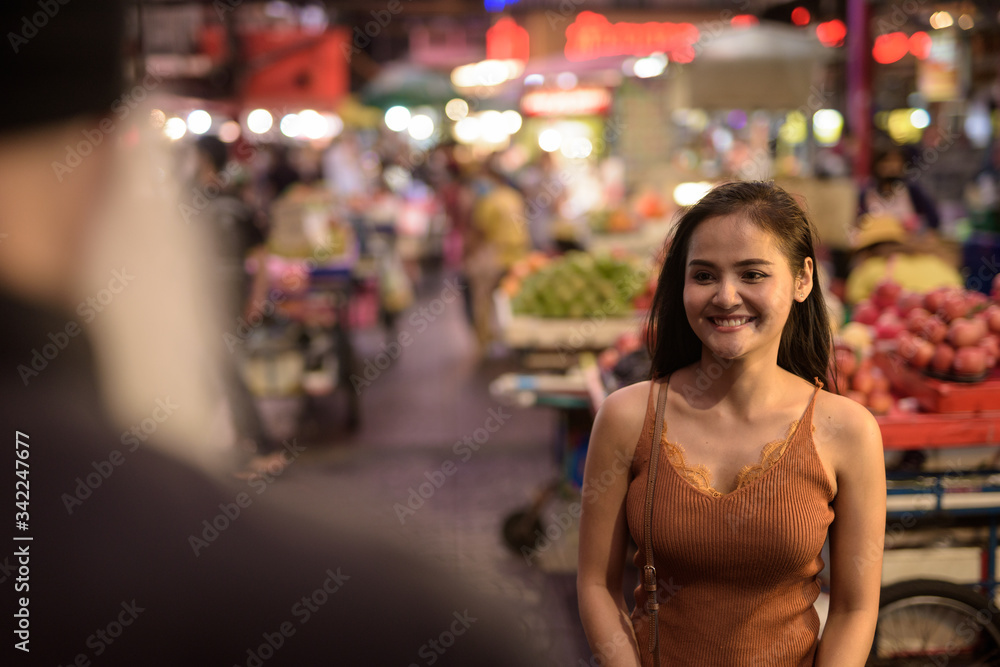 Friendly young Asian woman helping tourist man with directions in Chinatown at night