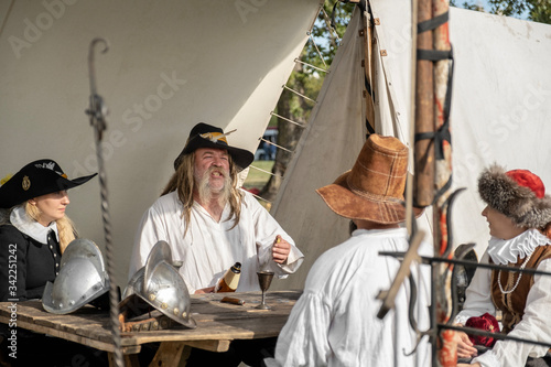Reconstruction of the Middle Ages. People in ancient costumes sitting behind a wooden desk and talking.