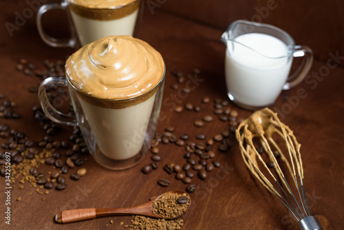 cold dalgon coffee in clear glasses on a dark wooden background. foam from sugar and instant coffee is whipped with a mixer over cold milk. Korean and Indian whipped coffee photo