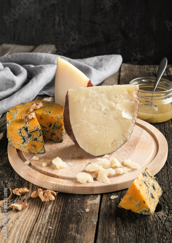 Pieces of Jugas and Shropshire Blue  cheese with grapes on a wooden plate at  background photo