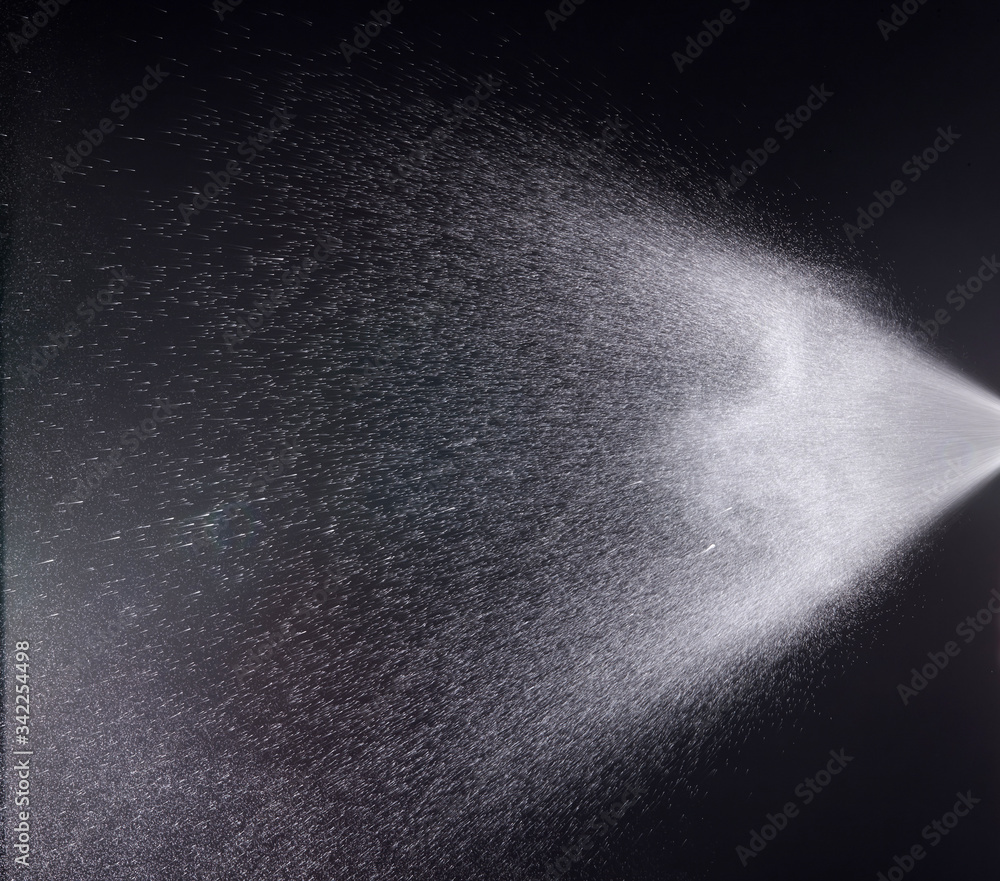 a spray of liquid in a black background. a spray of liquid in a black background.